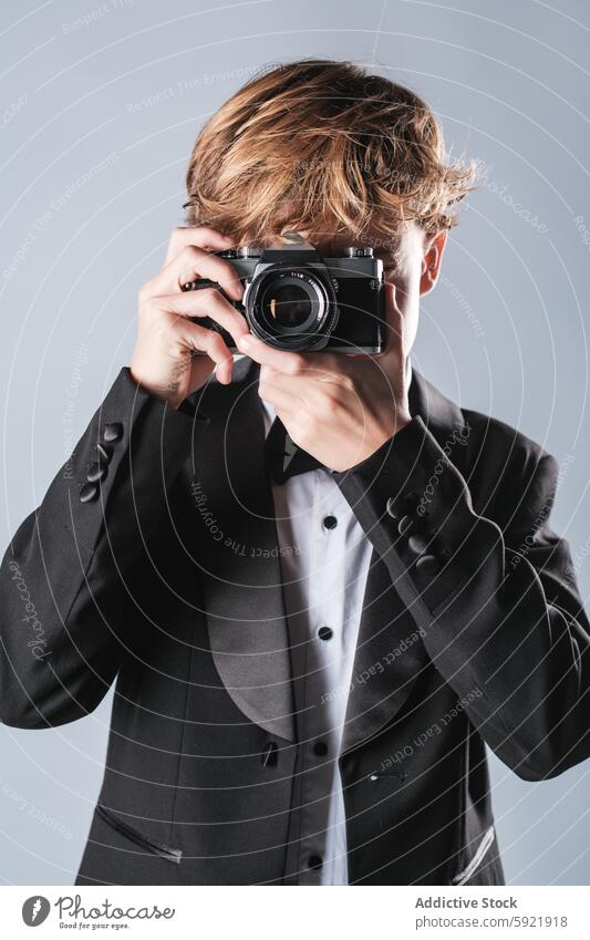 Jugendlicher mit Kamera im Studio fotografierend Junge Kind Anzug Fotoapparat formal Outfit positiv Gerät Schuljunge wenig Moment stilvoll unschuldig stehen