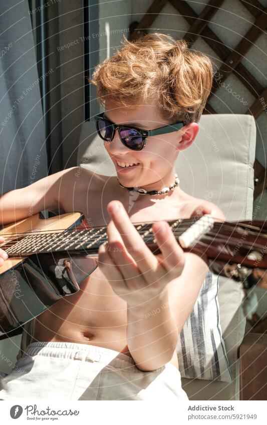 Junger Junge genießt Musik und spielt Gitarre im Freien Spielen jung Sonnenbrille sonnig Tag Freude Erholung Leidenschaft Musical Instrument Freizeit Aktivität