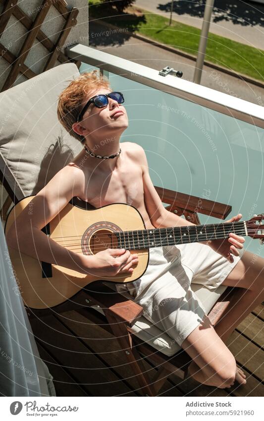 Junger Musiker genießt seine Gitarre an einem sonnigen Tag Kind Spielen Instrument Erholung Sommer Sonnenschein im Freien Freizeit Hobby akustisch jung Teenager