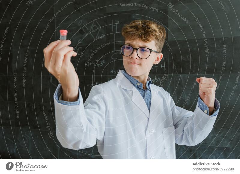 Junge zeigt Reagenzgläser, während er an der Tafel im Klassenzimmer steht Schule Chemie klug Reagenzglas Formel Experiment Klassenraum intelligent Schulkind