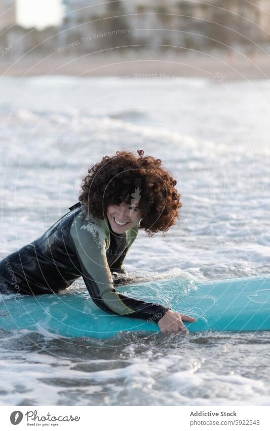 Lächelnde Frau im Neoprenanzug mit Surfbrett im wogenden Meer Surfer MEER winken genießen Strand sich[Akk] entspannen schäumen Küste Meerwasser Wasser platschen