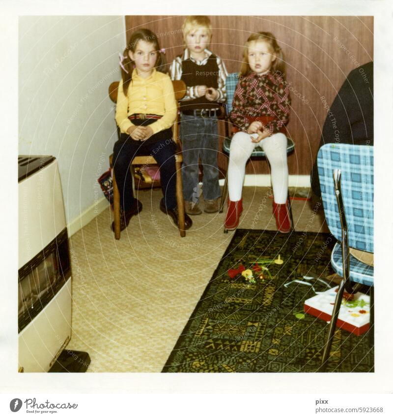 Polaroid aus den 70er Jahren, welches drei Kinder vor einer Holztapete zeigt Spielen Langeweile unwillig gelangweilt PVC küchenstuhl midcentury Flowerpower