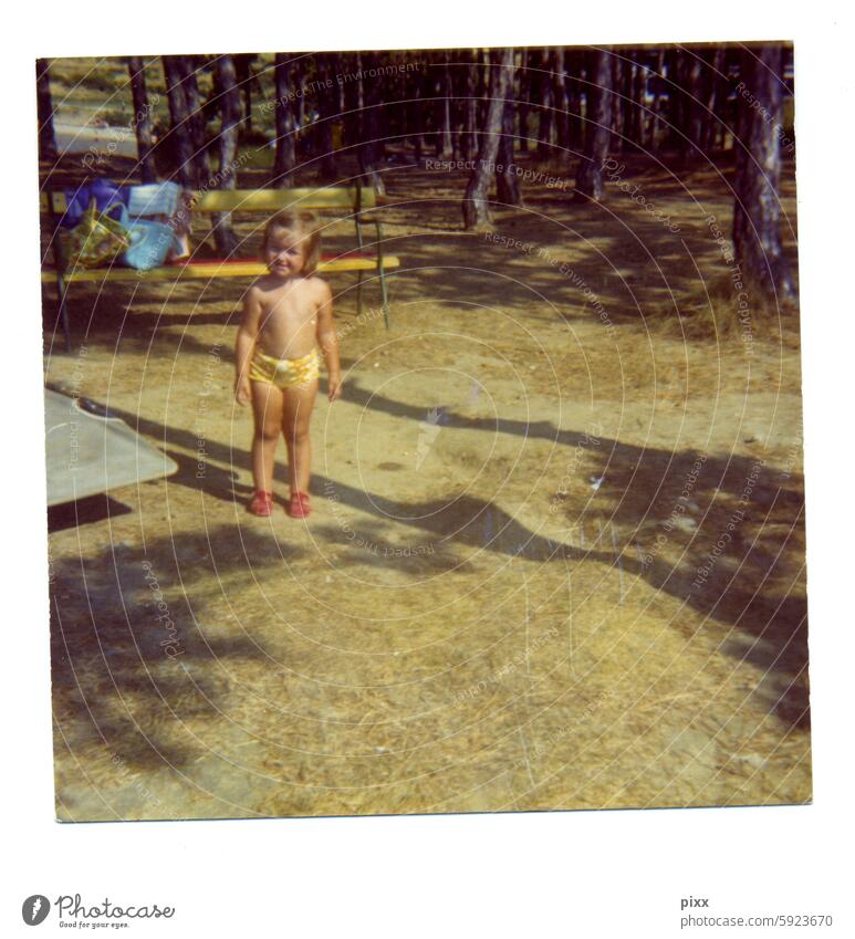 Polaroid von einem Kind im Sommerurlaub der 70er Jahre mit gelber kurzer Hose Frottée lächelnd Lächeln Schüchternheit schüchtern 2021 gummischuhe Sandalen