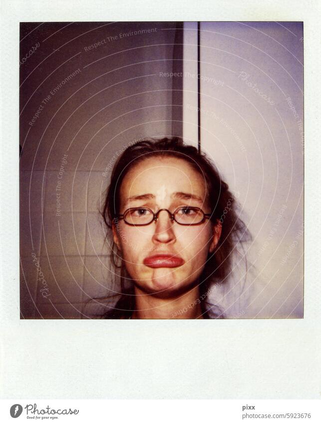 Polaroid einer Frau Anfang 20 mit kleiner Brille beim Grimasse schneiden vor Badezimmerwand Mund Lippen schmollen Farbstich Quadrat quadratisches Format