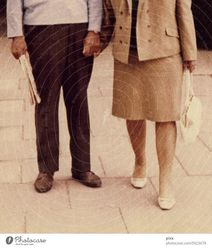 Foto aus den 60er jahren mit einem Paar das sich an der Hand hält Kostüm Handtasche Pumps Tageszeitung Ehepaar unten HandinHand beige hellblau chick ausgehen