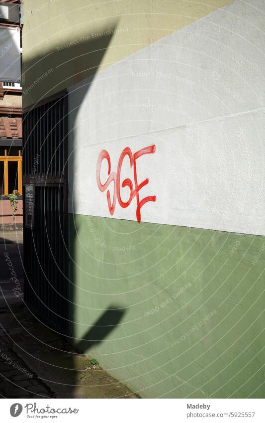 Graffiti mit Buchstaben in Rot auf der Wand einer Toreinfahrt in Naturfarben und Pastellfarben bei Sonnenschein in einem Hinterhof in der Schulstraße im Stadtteil Sachsenhausen in Frankfurt am Main in Hessen