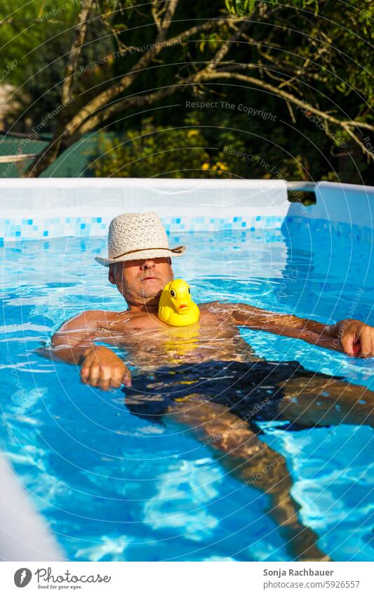 Ein Mann mit Sonnenhut und einer gelben Gummiente in einem Pool. Sommer Erholung Schwimmen & Baden Ferien & Urlaub & Reisen Sommerurlaub Wasser Erfrischung