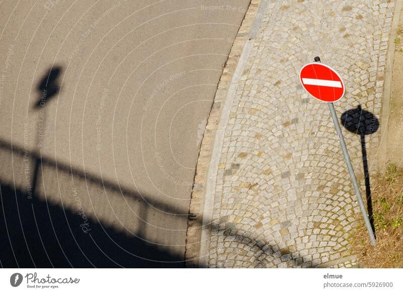 Blick von einer Brücke aus auf eine Straße mit gepflastertem Fußweg, einem Verkehrsschild " Verbot der Einfahrt " und Schatten Verkehrszeichen Einfahrt verboten