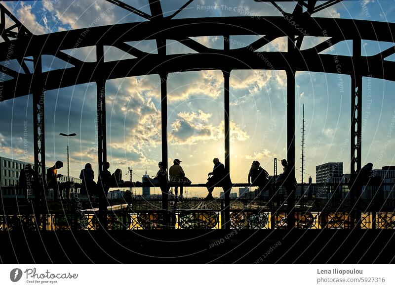 Silhouetten von jungen Leuten, die im Sonnenuntergang auf der Stahlbrücke sitzen voller Rahmen Hacker Brücke antik Architektur Hintergründe Gebäude Mitteleuropa