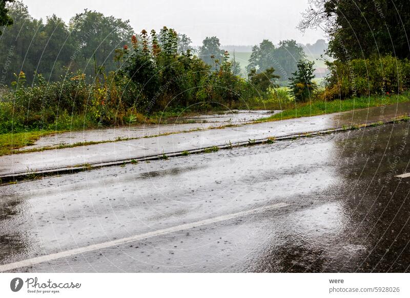 Starker Regen ergießt sich über eine Straße und bildet gefährliche Wasserpfützen h2o Starkregen liquide Aquaplaning Laufwerk Tropfen Überschwemmung Flüssigkeit