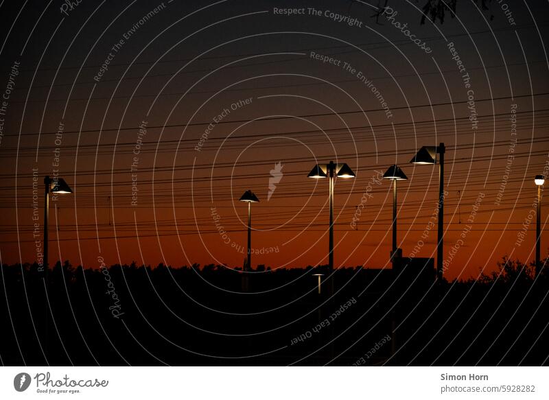 Lichtstimmung aus Abenddämmerung und einer Vielzahl von Straßenlaternen Laternen Lichtquellen Nachteinbruch Beleuchtung Lichtschein Abendrot Dämmerung