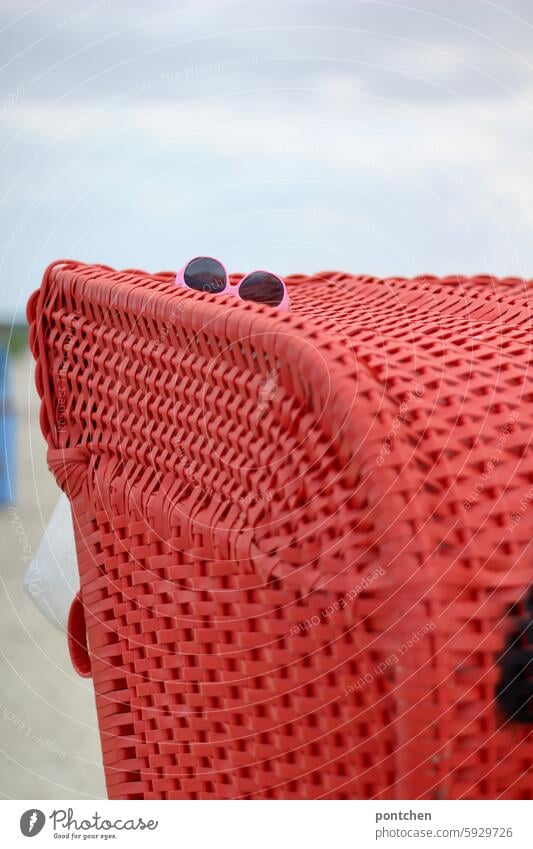 lost and found. fundstück. eine pinke sonnenbrille liegt auf einem roten strandkorb farbkontrast urlaub verloren verlust Reise nordsee