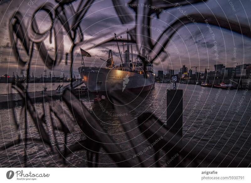 Museumsschiff Cap San Diego im Hamburger Hafen zur blauen Stunde hinter einer mit Graffiti beschmierten Glasscheibe Blaue Stunde Hafenromantik Hafenstadt