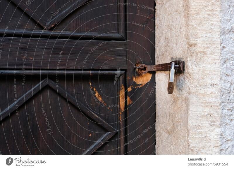 Verwitterte braune Holztür mit einem Vorhängeschloss Antiquität Gebäudeeingang Nahaufnahme zugeklappt Tür Türöffnung Gate Haus bügeln Schnappriegel Schloss