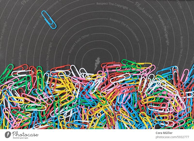 bunte Büroklammern auf einer schwarzen Tafelfäche Hintergrund Klammer Textfreiraum viele Kontrast grafisch einzeln Fläche Textur anheften rot blau gelb weiß