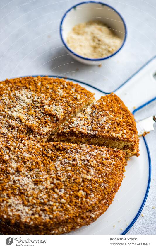 Draufsicht auf geschnittenen hausgemachten Honigkuchen mit Belag Kuchen selbstgemacht Dessert süß backen Gebäck zerkleinerte Nüsse Teller blau umrandet