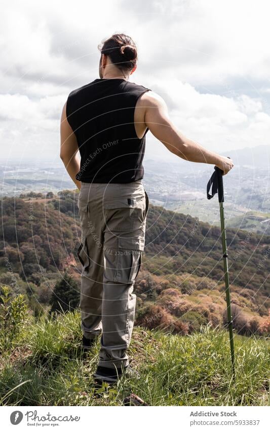 Rückenansicht eines in der Natur stehenden Mannes mit Wanderstock Rückansicht unkenntlich anonym gesichtslos wandern im Freien Abenteuer Landschaft reisen Hügel