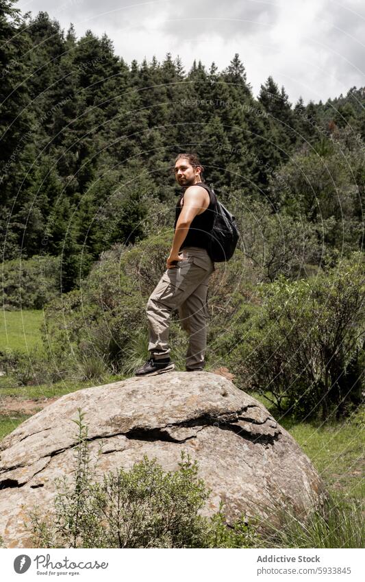 Junger Mann wandert auf einem felsigen Gelände, umgeben von üppigem Grün wandern Natur Wald grün im Freien Abenteuer Freizeit Landschaft lässig Kleidung