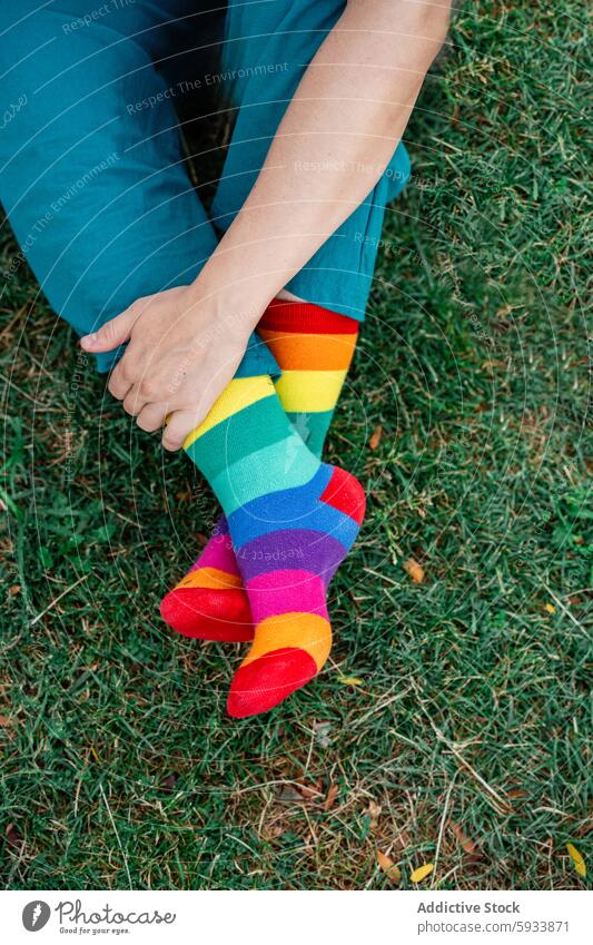 Person mit bunten lgbt Regenbogen Socken sitzen auf grünem Gras lesbisch Kniestrümpfe farbenfroh Sitzen blaugrün Höschen im Freien Komfort lässig entspannt