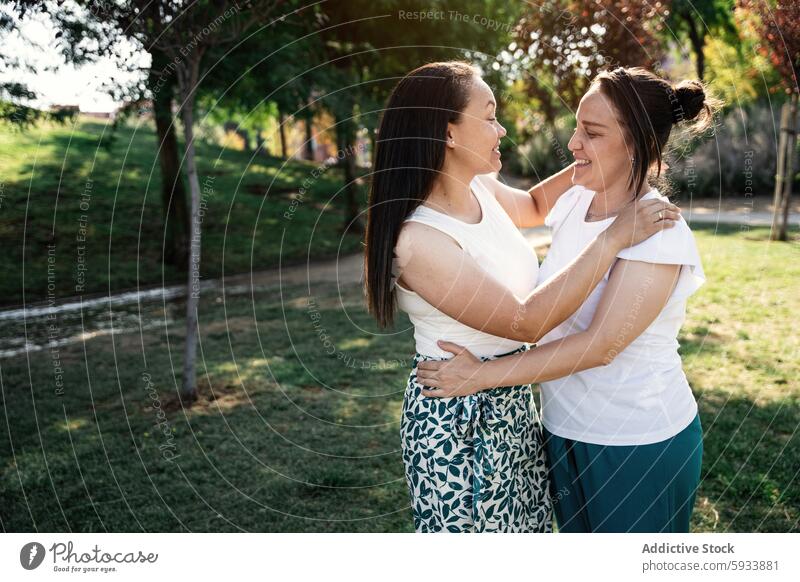 Zwei lesbische kolumbianische Frauen umarmen und lächelnd in einem Park mit Grünpflanzen lgbt Paar Umarmen Lächeln Natur im Freien Freundschaft Zuneigung Freude