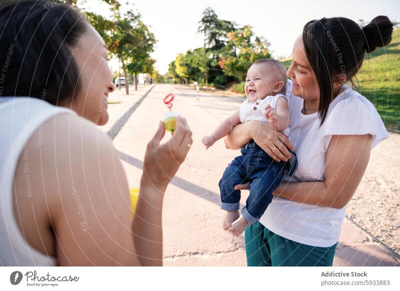 Generiertes Bild Familie lesbisch Paar Frau Mutter Sohn Baby Kind Park im Freien tagsüber Sommer Freizeitkleidung Jeanshose T-Shirt Gras Spielzeug Lächeln