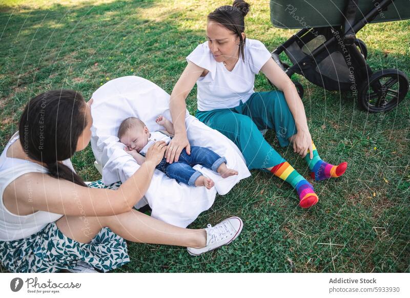 Lesbisches Paar kümmert sich um Baby im Kinderwagen im Park Mutter lesbisch lgbt Gras im Freien kolumbianisch Bonden Liebe Pflege Familie ruhen schlafen