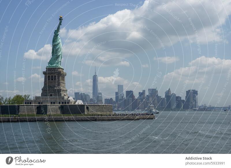 Ikonischer Blick auf die Freiheitsstatue und die Skyline von Manhattan Statue New York State Architektur Wasser Fluss Boot Cloud Denkmal Wahrzeichen Großstadt