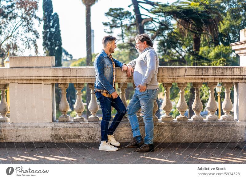 Schwules Paar genießt einen sonnigen Tag an einer historischen Balustrade schwul Männer Liebe Park Bäume Architektur Gesellschaft Lehnen Glück Jeansjacke