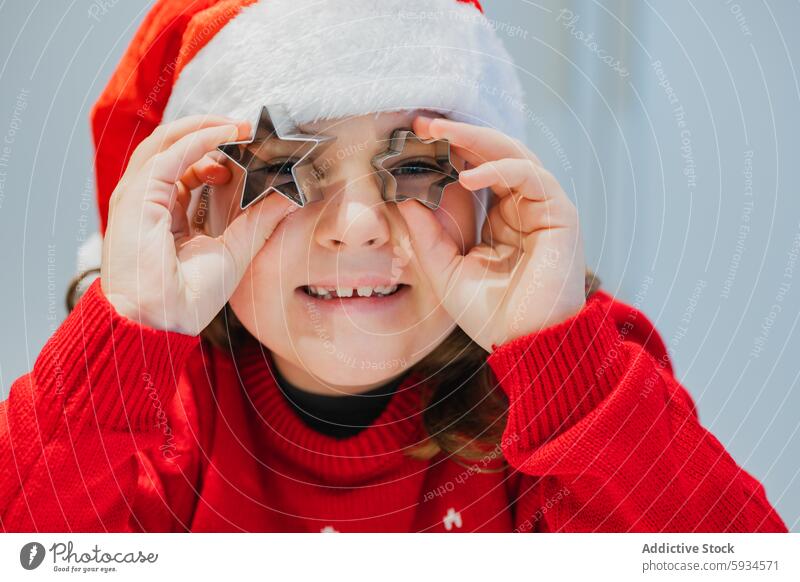 Festliches Mädchen spielt mit Ausstechformen Zwilling Weihnachten festlich spielen Weihnachtsmütze roter Pullover Freude Feiertag Essen zubereiten backen Kind