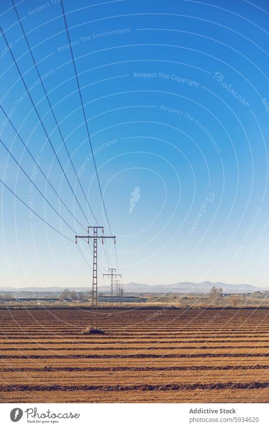 Strommasten, die sich über die ländliche Landschaft erstrecken elektrisch Pylon Stromleitung Feld gepflügt Himmel übersichtlich blau ruhig Szene Elektrizität