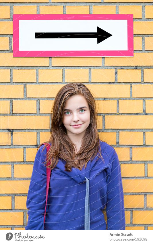 Lächelndes Mädchen vor einer Backsteinmauer/Richtungspfeil Lifestyle Mensch feminin Frau Erwachsene Jugendliche 1 13-18 Jahre Kind Mauer Wand brünett Zeichen