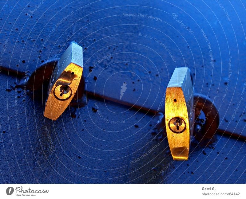 zwei goldene Vorhängeschlösser mit Schlüsselloch an blauer Oberfläche Sicherheit schließen geschlossen Vorhängeschloss 2 Zusammensein Licht Stimmung Dämmerung