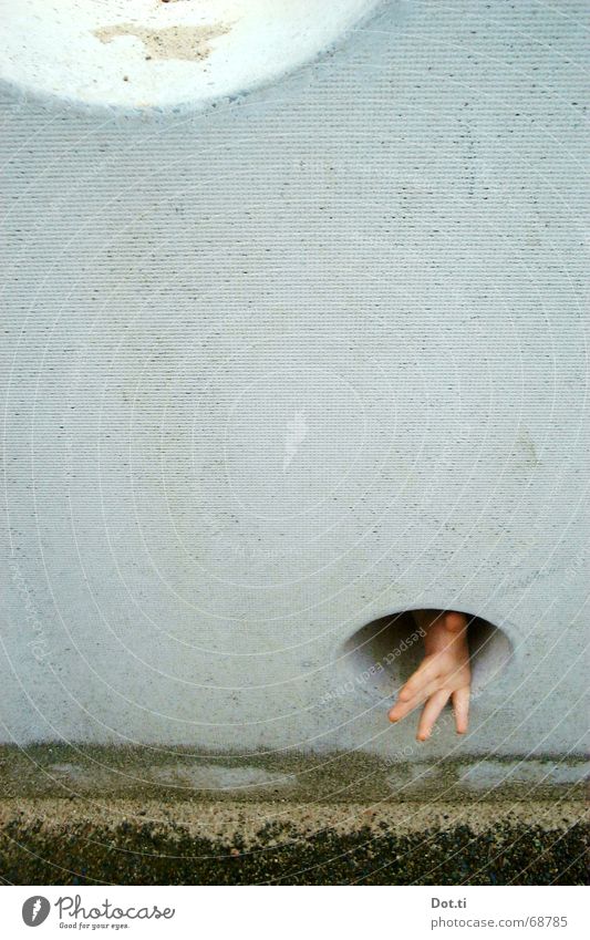 Kinderhand greift durch ein Loch in einer Betonwand Freude Spielen Hand Finger 1 Mensch Sand Spielplatz Mauer Wand bedrohlich klein trist grau Angst