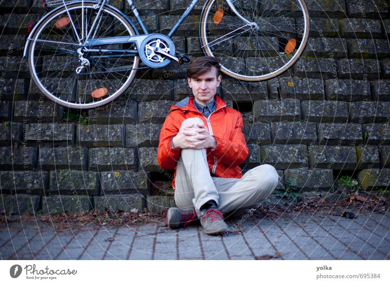Junger Mann mit Fahrrad, der draußen auf dem Boden posiert. Mensch maskulin Jugendliche 1 18-30 Jahre Erwachsene Jugendkultur Umwelt Frühling Herbst Stadt Mauer