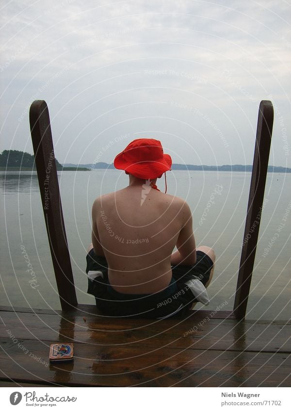 Einsamer Bube See nass Reflexion & Spiegelung Holz Badehose flo Wasser Regen Körper Rücken Hut orange Schwimmen & Baden