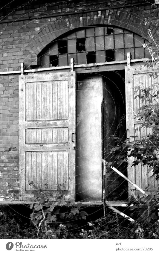 alte Tür s/w Holztür Schiebetür Schiebetor Fenster kaputt gebrochen zerschlagen oben Splitter Bogen Backstein Gießerei Handwerk dreckig vergessen Einsamkeit