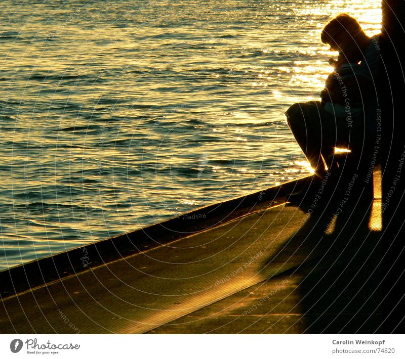 Vater und Sohn Licht Wellen Mann Sonnenuntergang Abenddämmerung Hafen Leben Wasser Schatten Anlegestelle Am Rand Textfreiraum links Mole Gegenlicht Warmes Licht