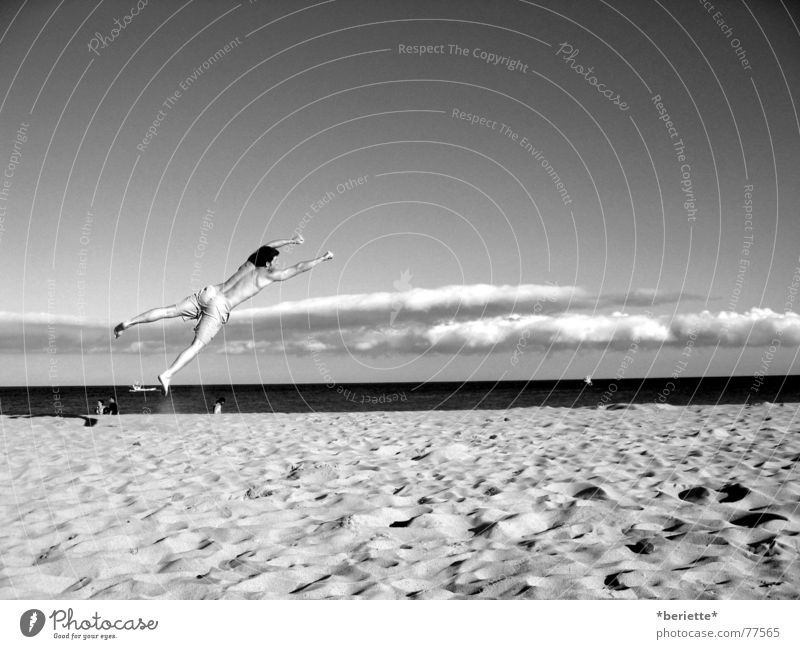 Freiheit 2 Mann Badehose springen Strand Physik Sommer Meer nass salzig Wolken drehen toben schwarz weiß Muskulatur Wärme Himmel blau Sand Freude lustig