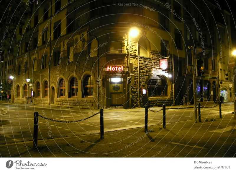 Hotel Farbfoto Außenaufnahme Menschenleer Nacht Licht Schatten Zentralperspektive Haus Lampe Gastronomie Stadt Tor Gebäude Tür Straße Straßenkreuzung