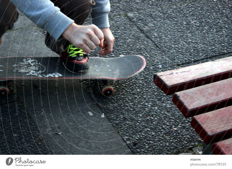 VOR DEM SPRUNG fahren springen hüpfen Beginn Schuhbänder Knie London Underground Skateboarding gebeugt Erwartung Nervosität aufregend Spannung Asphalt grün Hand