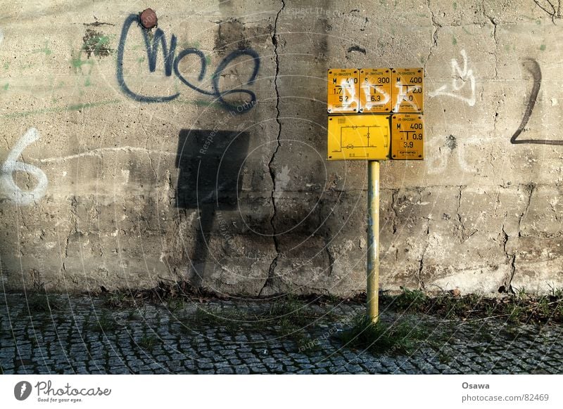 Hydrantensprache Grasbüschel erschließen gelb Wand Beton Zement Bürgersteig Installationen elektronisch Installateur Anschluss Versorgung Gasse Riss Schatten