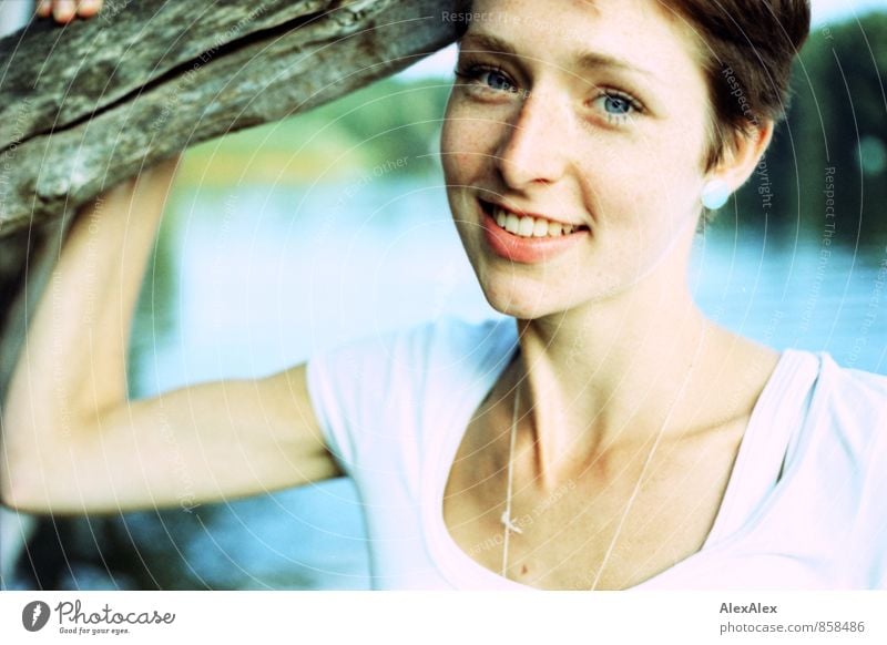 schlanke, junge Frau steht am Ufer des Badesees an einem Baum gelehnt Junge Frau Jugendliche Gesicht Sommersprossen 18-30 Jahre Erwachsene Ast Seeufer T-Shirt