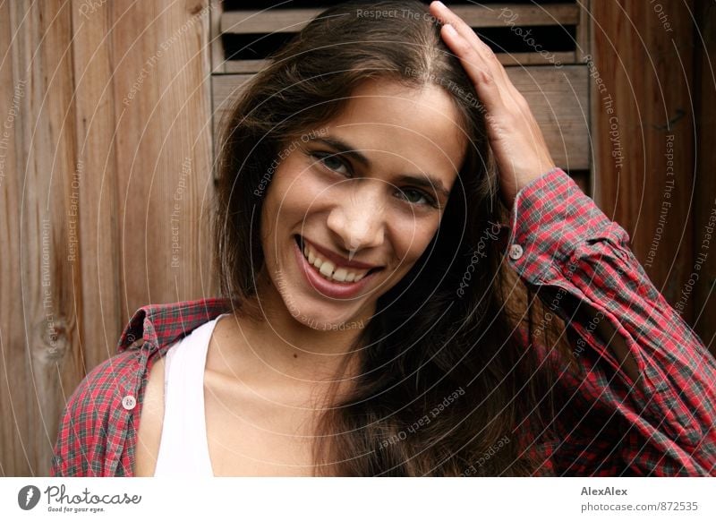 Portrait einer jungen, schönen, lachenden Frau vor einer Holztür Junge Frau Jugendliche 18-30 Jahre Erwachsene Hemd Unterhemd brünett langhaarig Kommunizieren