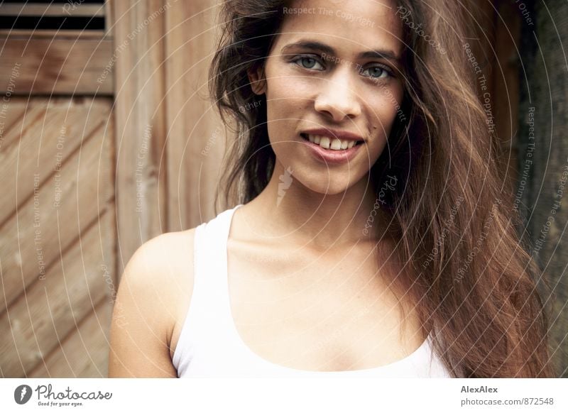Portrait einer schönen, jungen, lächelnden Frau vor einer Holztür Junge Frau Jugendliche Gesicht 18-30 Jahre Erwachsene Unterhemd schwarzhaarig langhaarig