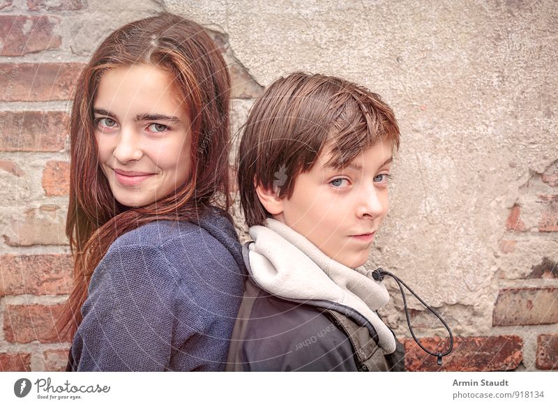 Porträt zweier Geschwister, Rücken an Rücken Lifestyle Winter Mensch maskulin feminin Bruder Schwester Jugendliche 2 13-18 Jahre Kind Mauer Wand Lächeln
