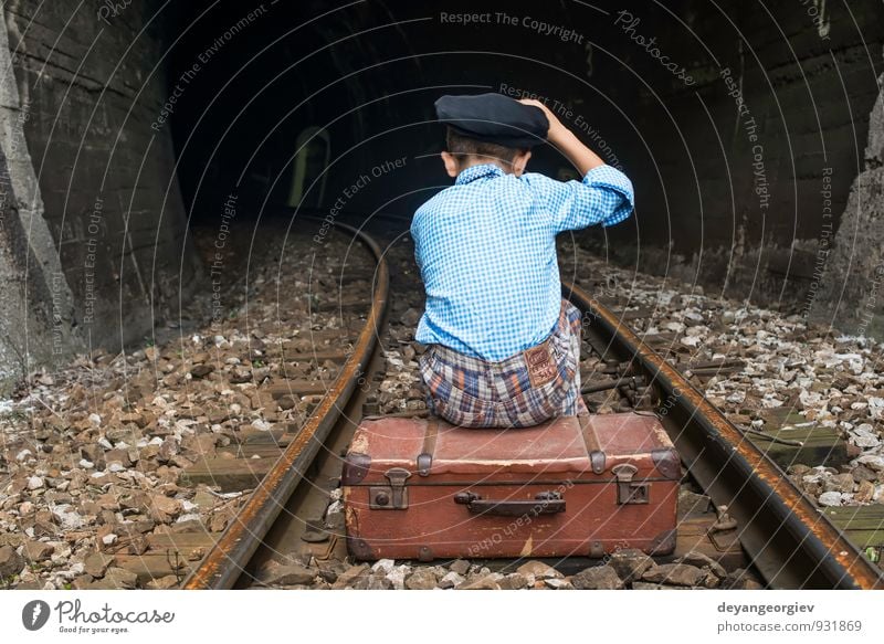 Kind in Vintage-Kleidung sitzt auf der Eisenbahnstrecke. Ferien & Urlaub & Reisen Ausflug Mensch Mädchen Junge Kindheit Natur Verkehr Koffer fallen sitzen
