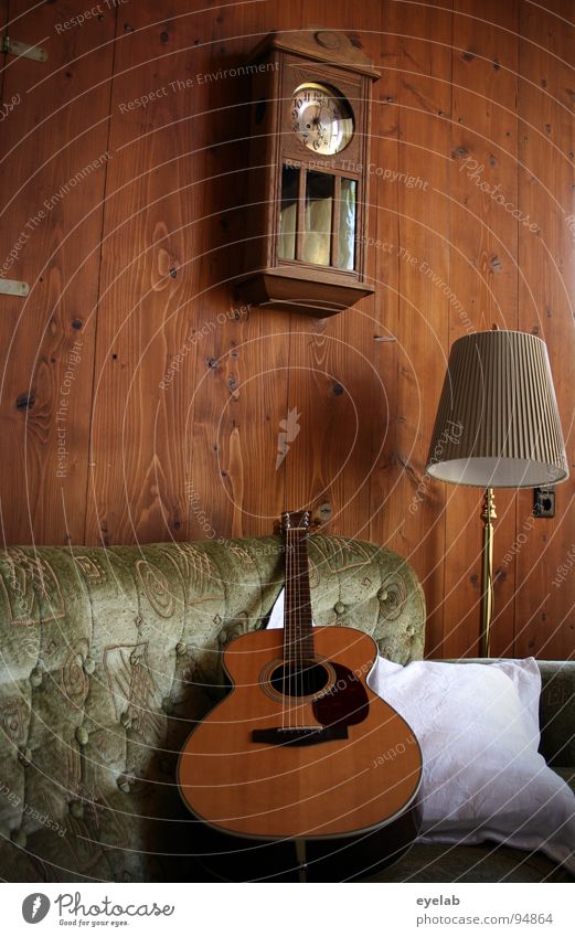 Gemütlichkeit ist keine Frage der Einstellung Wand Holz Wandtäfelung Westerngitarre Sofa Sitzgelegenheit bequem Lampe Stehlampe Wanduhr Uhr analog Kissen
