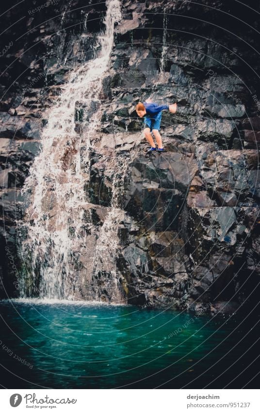 Sich fallen lassen, Junge springt von einem Felsen in einen See. Neben ihm ist ein Wasserfall. Auf der Insel Prince of Wales. Torres Strait Inseln.Australia