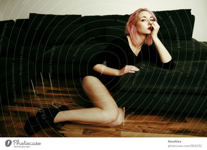 junge, langbeinige Frau mit pinken Haaren sitzt vor der Couch Häusliches Leben Wohnung Sofa Holzfußboden Junge Frau Jugendliche Gesicht Beine 18-30 Jahre