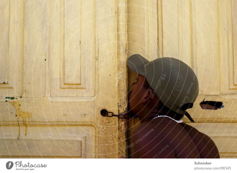 Der Gerüchteflüsterer Flüstern geheimnisvoll sprechen tratschen Mütze Brasilien Baseballmütze Mensch Tür Spalte geheimniss Junge Tor Salvador de Bahia wisper